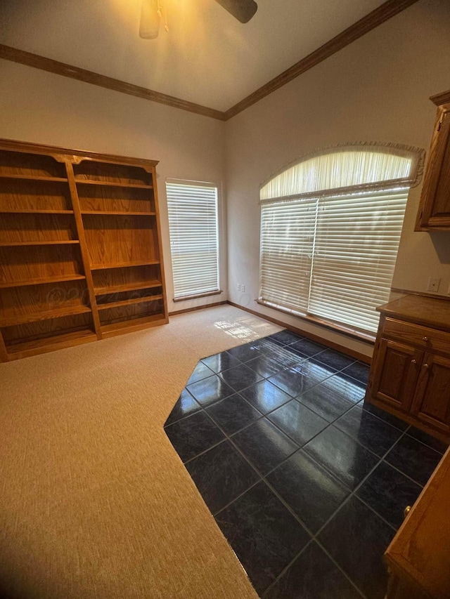 interior space featuring dark colored carpet, ceiling fan, and crown molding