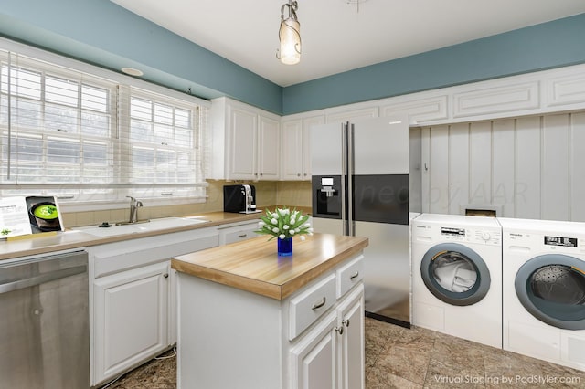 clothes washing area featuring laundry area, washing machine and dryer, a sink, and stone finish flooring