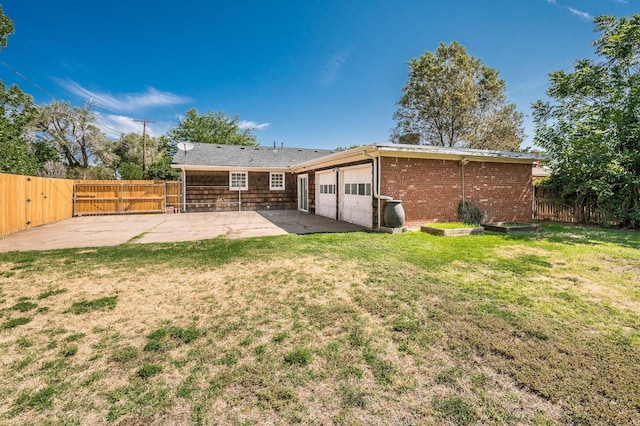 back of property featuring brick siding, a yard, a patio area, a garage, and a fenced backyard