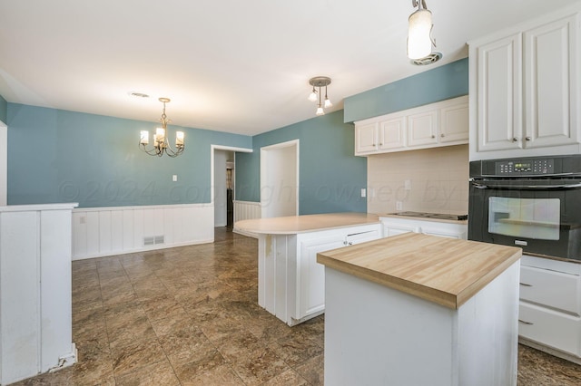 kitchen featuring oven, a peninsula, wood counters, white cabinetry, and wainscoting