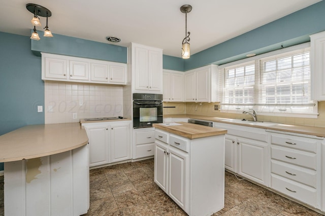 kitchen with decorative backsplash, white cabinets, a peninsula, a sink, and black oven