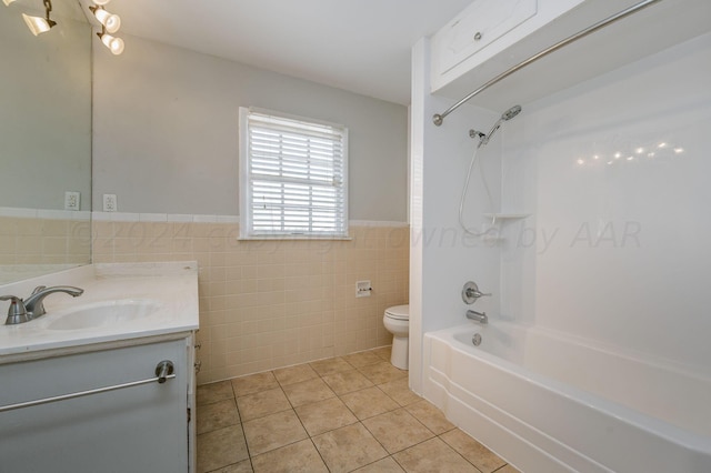 full bathroom featuring tile patterned flooring, toilet, vanity, tile walls, and shower / washtub combination