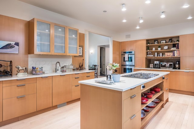 kitchen with stainless steel appliances, light brown cabinetry, a kitchen island, and light hardwood / wood-style flooring