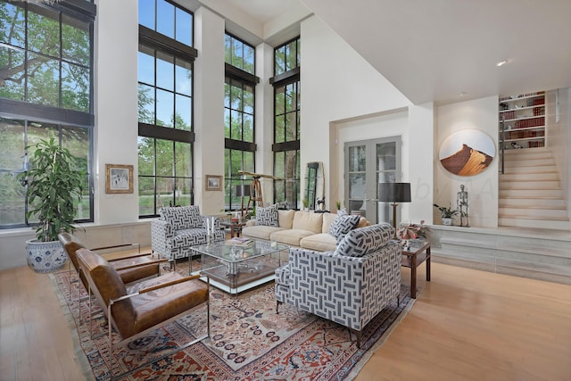 living room featuring a wealth of natural light, a high ceiling, and light hardwood / wood-style flooring