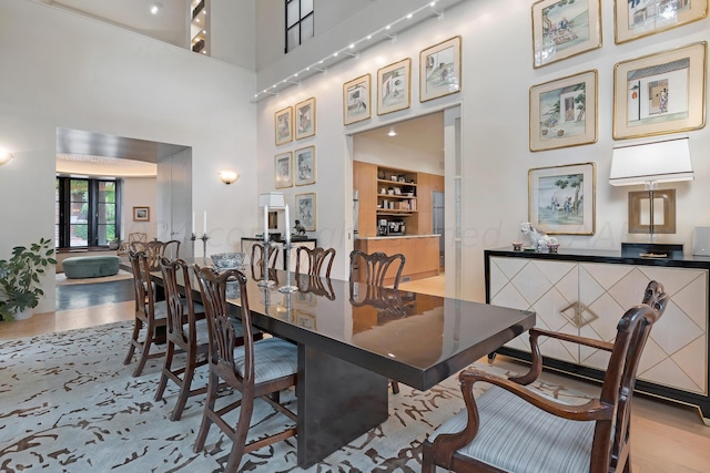 dining space featuring a towering ceiling and light hardwood / wood-style floors