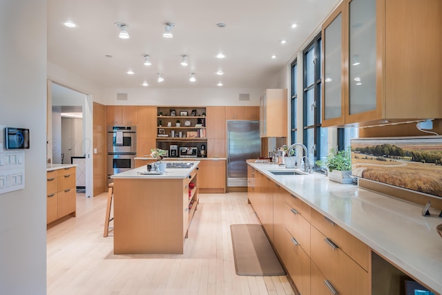 kitchen featuring stainless steel appliances, a kitchen island, light wood-type flooring, sink, and a breakfast bar area