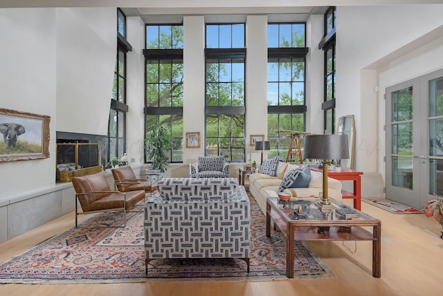 living room featuring hardwood / wood-style floors, a wealth of natural light, a high ceiling, and french doors