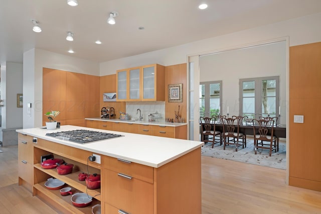 kitchen with a kitchen island, light wood-type flooring, sink, and stainless steel gas stovetop