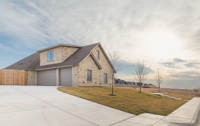 exterior space with fence, an attached garage, a front lawn, brick siding, and driveway
