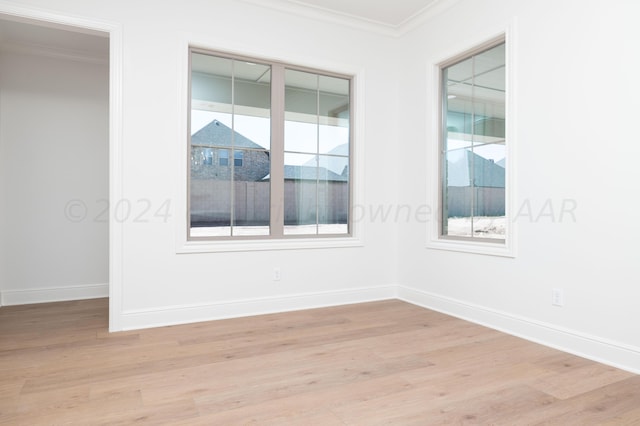 empty room with baseboards, ornamental molding, and light wood finished floors
