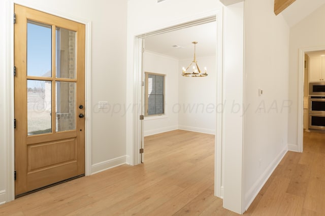 entryway with an inviting chandelier, baseboards, ornamental molding, and light wood-type flooring