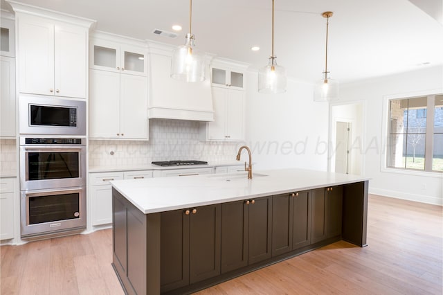 kitchen with backsplash, visible vents, a sink, stainless steel appliances, and white cabinetry