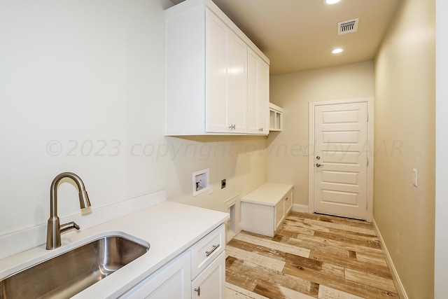 laundry room featuring electric dryer hookup, cabinets, sink, hookup for a washing machine, and light wood-type flooring