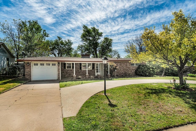 ranch-style house featuring a chimney, brick siding, a front yard, concrete driveway, and an attached garage