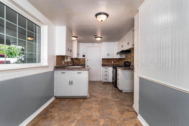 kitchen with electric stove, white cabinets, dark countertops, and a sink