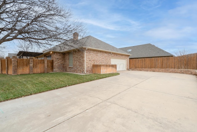 view of side of property with driveway, a lawn, an attached garage, fence, and brick siding