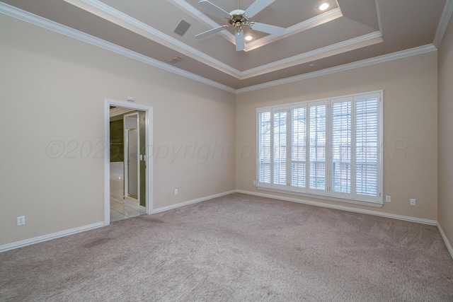 empty room featuring a raised ceiling, a ceiling fan, light carpet, baseboards, and ornamental molding