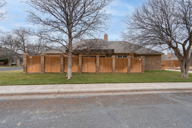 view of property exterior with brick siding, a yard, a fenced front yard, and a chimney