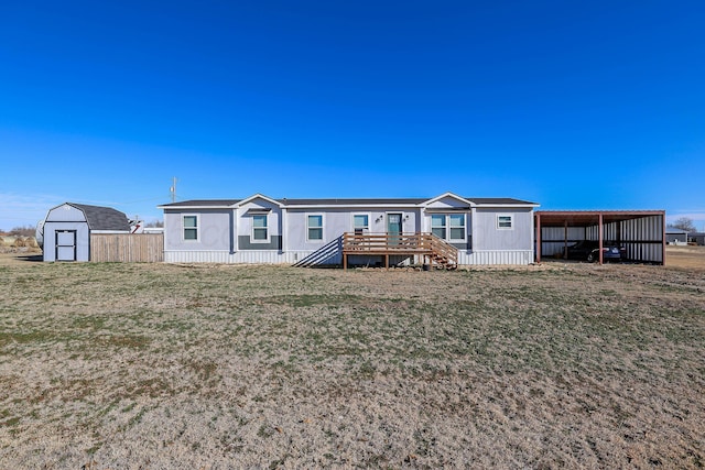 707 Trice St, Claude, TX 79019 - rear view of property with a deck, a shed, a carport, a lawn, and an outbuilding