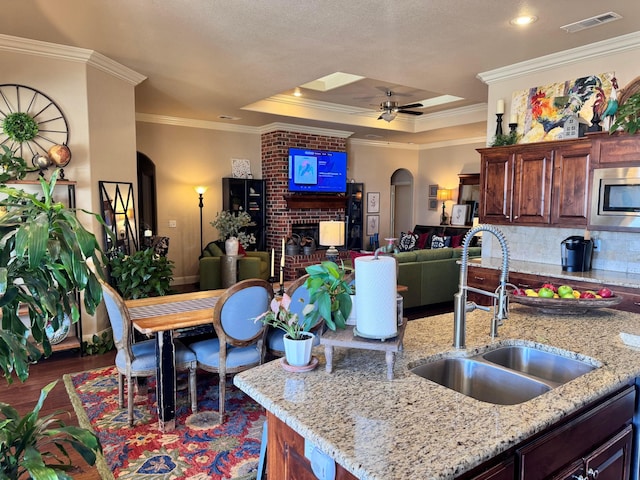 kitchen featuring stainless steel microwave, sink, and light stone countertops