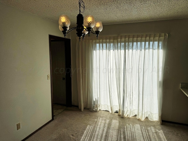 106 Middle St, Balko, OK 73931 - unfurnished room featuring plenty of natural light, an inviting chandelier, a textured ceiling, and carpet