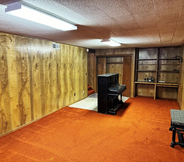 106 Middle St, Balko, OK 73931 - basement with wooden walls, carpet flooring, and a textured ceiling