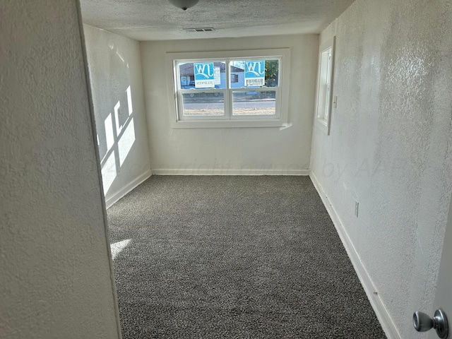 carpeted empty room with a textured ceiling