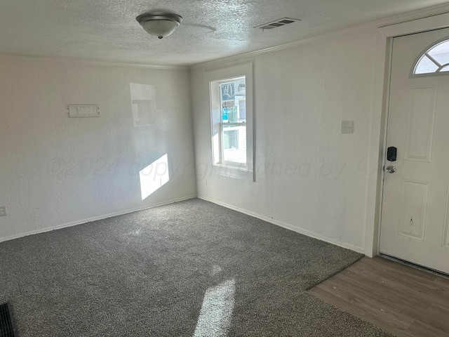 entrance foyer featuring a textured ceiling and dark carpet