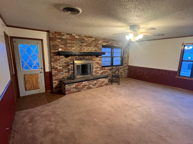 unfurnished living room featuring crown molding, a brick fireplace, carpet, and a textured ceiling