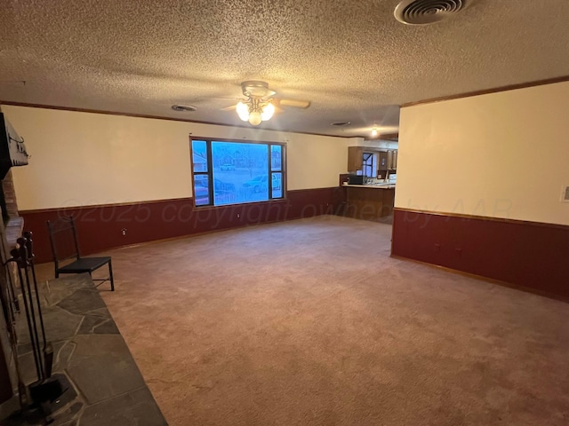 carpeted empty room featuring wooden walls, ornamental molding, and a textured ceiling