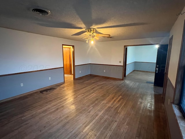 empty room with ceiling fan, dark hardwood / wood-style flooring, and a textured ceiling