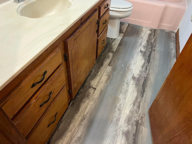 bathroom with vanity, a bathing tub, hardwood / wood-style floors, and toilet