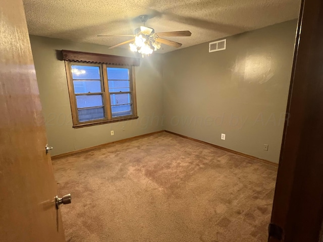 empty room with ceiling fan, light carpet, and a textured ceiling