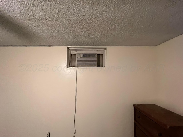 room details featuring a wall unit AC and a textured ceiling