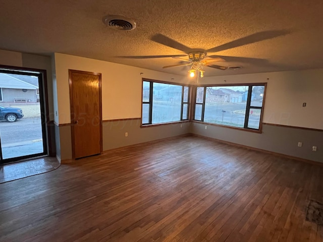 spare room featuring ceiling fan, dark hardwood / wood-style flooring, a textured ceiling, and a wealth of natural light