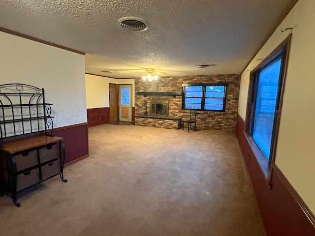 living room featuring brick wall, carpet, crown molding, a brick fireplace, and a textured ceiling