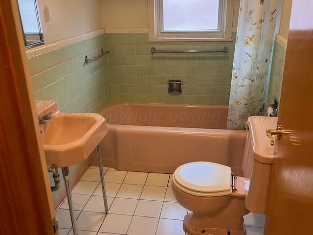 bathroom featuring tile patterned flooring, toilet, tile walls, and shower / tub combo