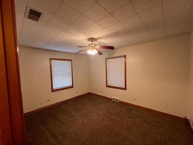 empty room with ceiling fan and dark carpet