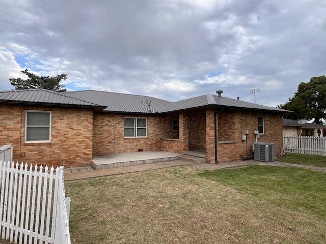 back of house with central AC unit, a yard, and a patio area