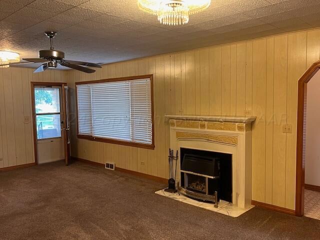 unfurnished living room featuring wood walls, ceiling fan, and carpet floors