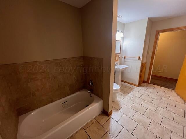 bathroom with a bath, tile patterned floors, toilet, and sink