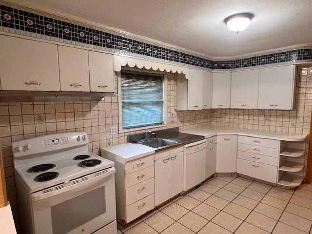 kitchen with white appliances, sink, light tile patterned floors, and white cabinets