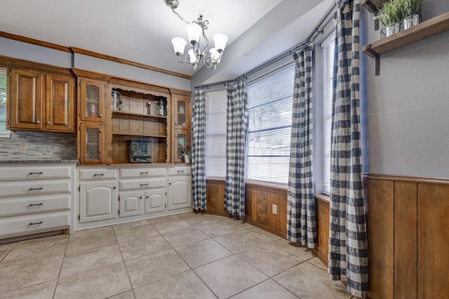 3409 Harmony St, Amarillo, TX 79109 - dining space featuring a chandelier, a wainscoted wall, wooden walls, light tile patterned floors, and crown molding