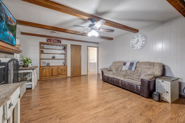 3409 Harmony St, Amarillo, TX 79109 - living area featuring a textured ceiling, wood finished floors, a ceiling fan, a large fireplace, and beamed ceiling