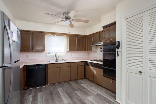 kitchen featuring sink, black appliances, ceiling fan, light wood-type flooring, and decorative backsplash