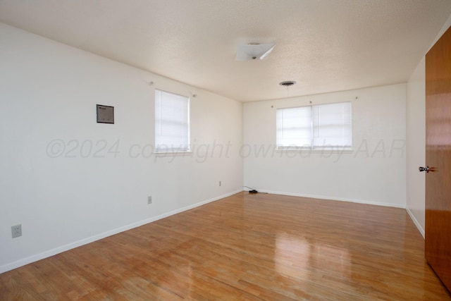 unfurnished room with hardwood / wood-style floors and a textured ceiling