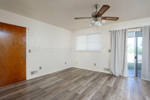 unfurnished room with a textured ceiling, a wealth of natural light, wood-type flooring, and ceiling fan