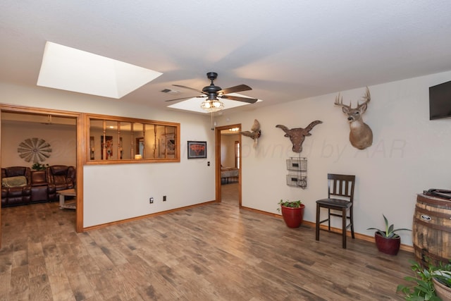 interior space with visible vents, ceiling fan, wood finished floors, and a skylight