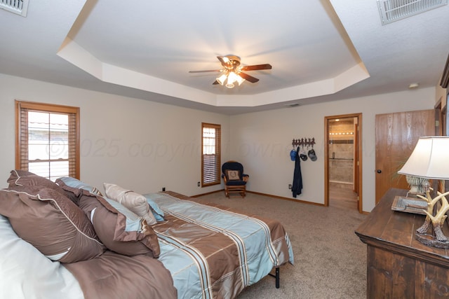 carpeted bedroom with a raised ceiling, baseboards, ceiling fan, and visible vents