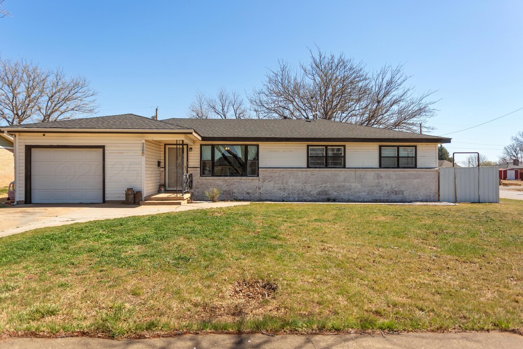 single story home with a front yard, an attached garage, fence, and concrete driveway